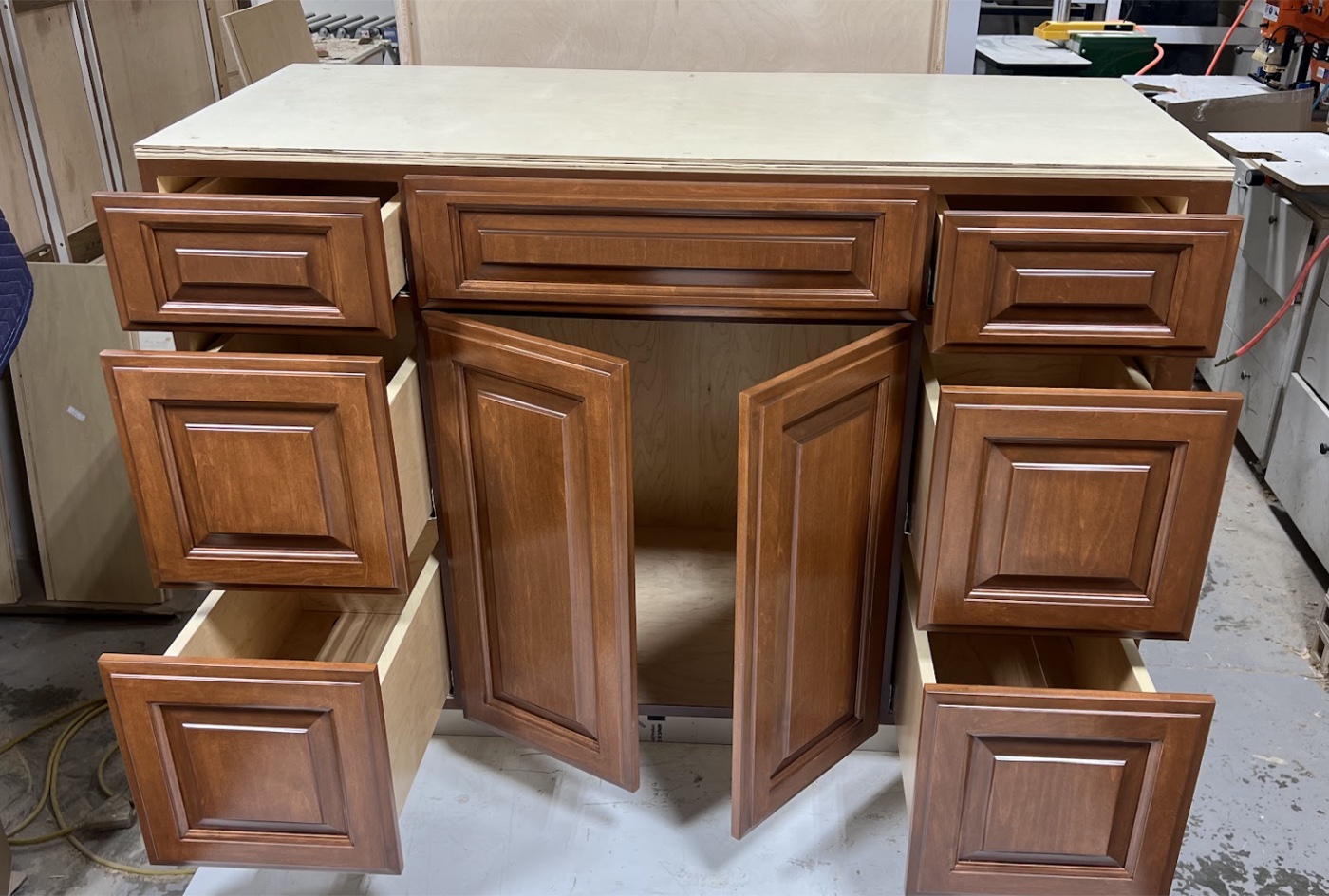 Brown raised-panel cabinet with its doors and drawers open in the Atrics shop