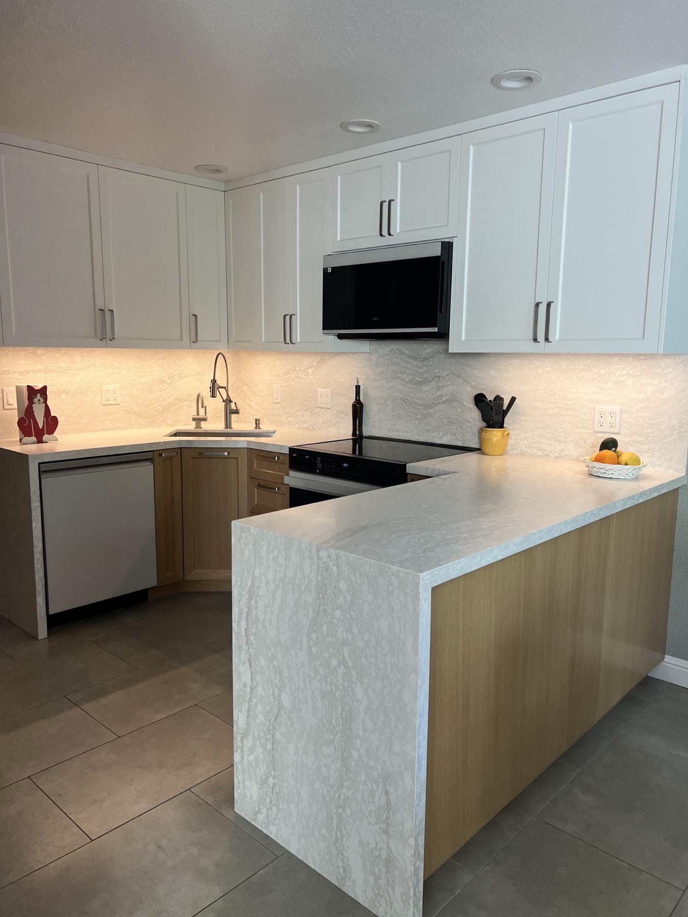 White upper cabinets above the sink corner with under-cabinet lighting on the backsplash