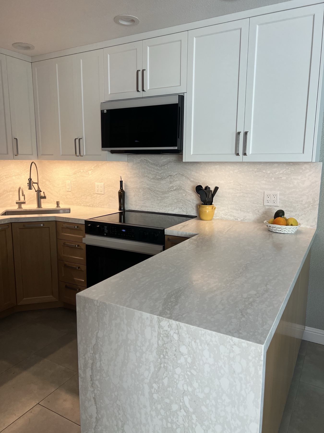 Stone counter running from the range to the peninsula with a matching backsplash