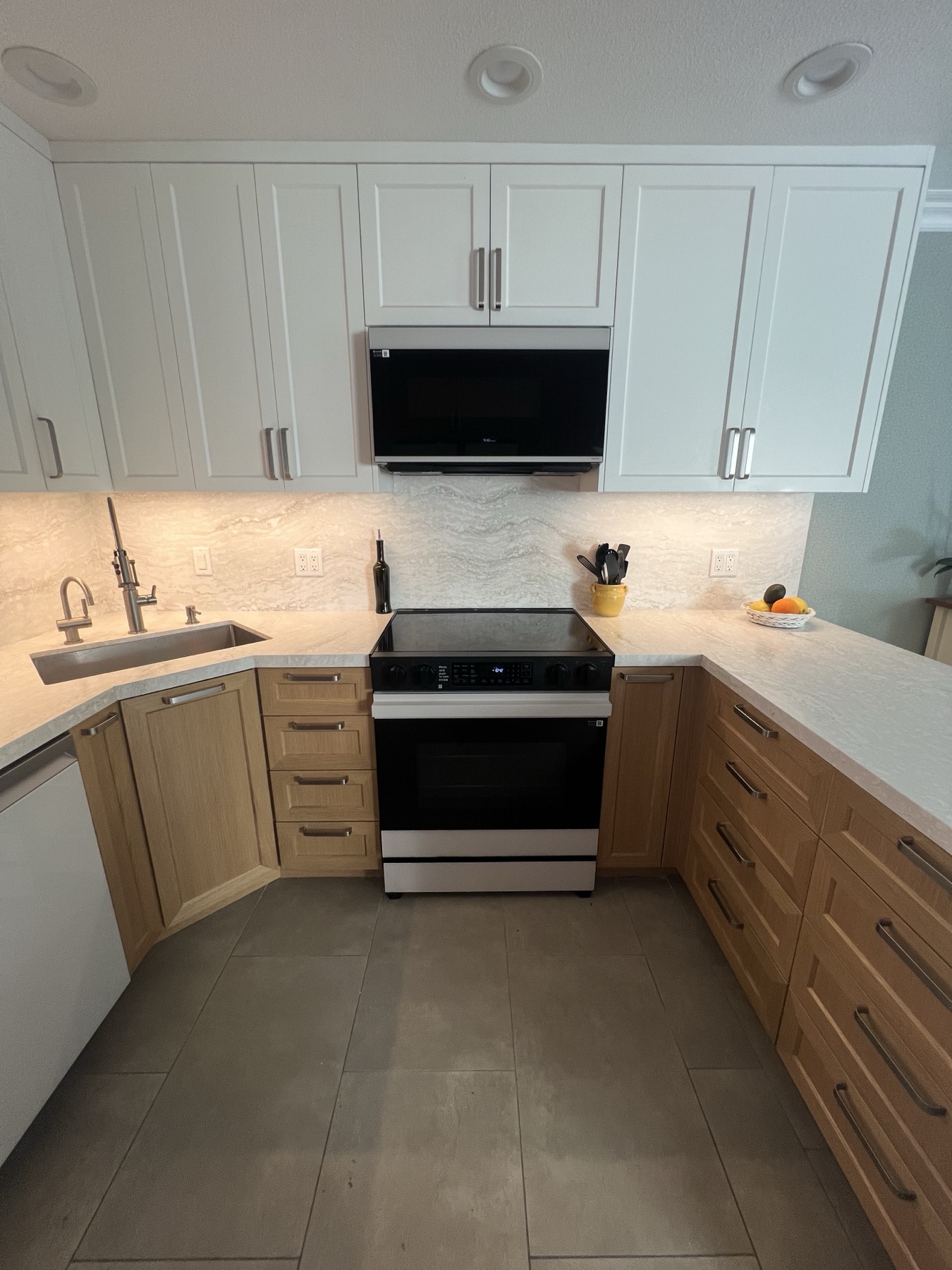 White upper cabinets to the ceiling across the range wall, with the microwave built in above the range