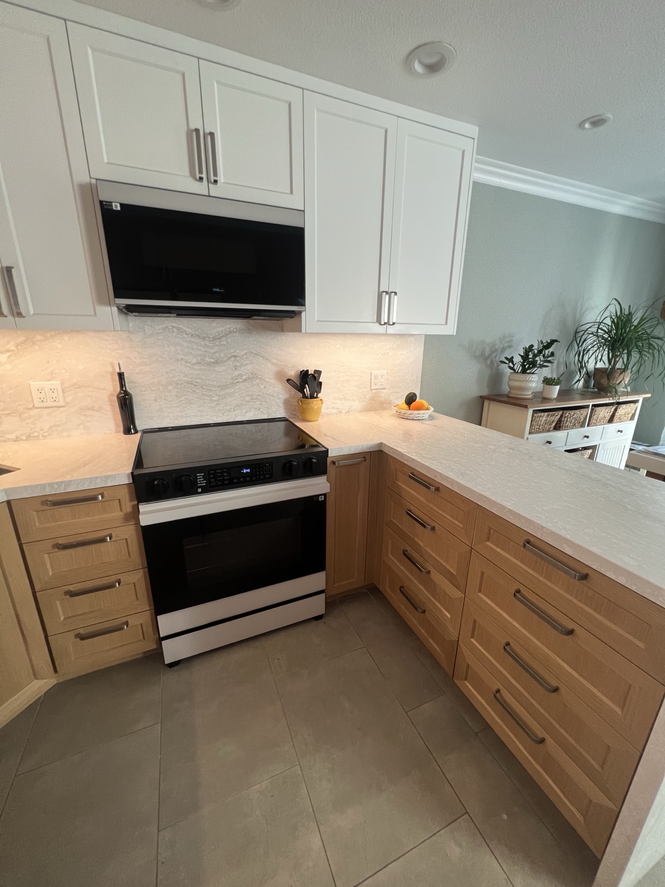 White upper cabinets turning the corner toward the window, lit from below