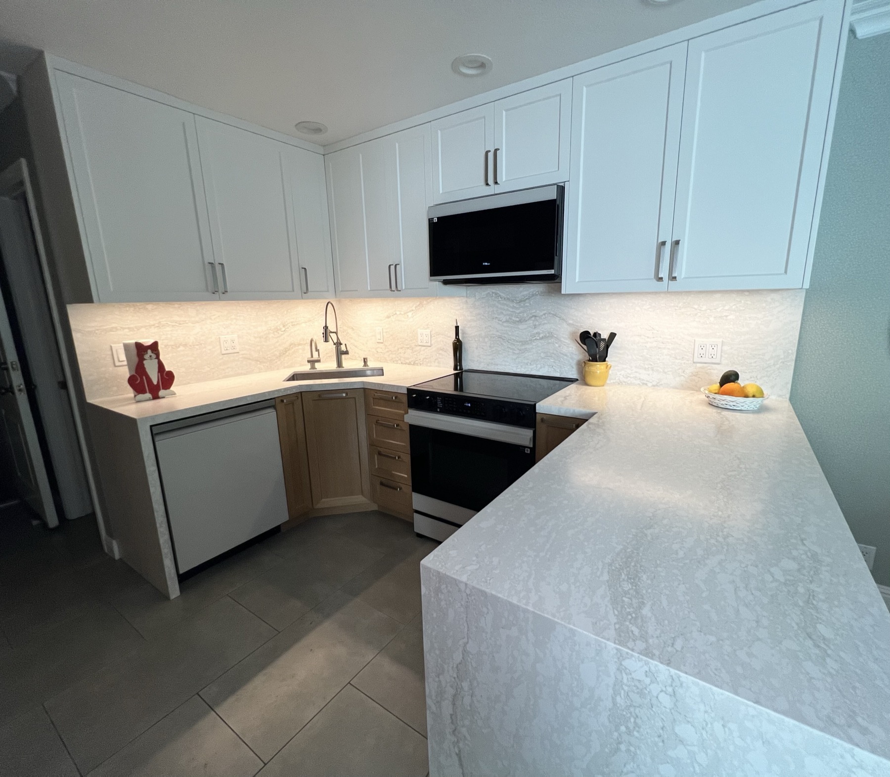 Kitchen from the peninsula showing brushed bar pulls on white upper doors and warm-wood drawers