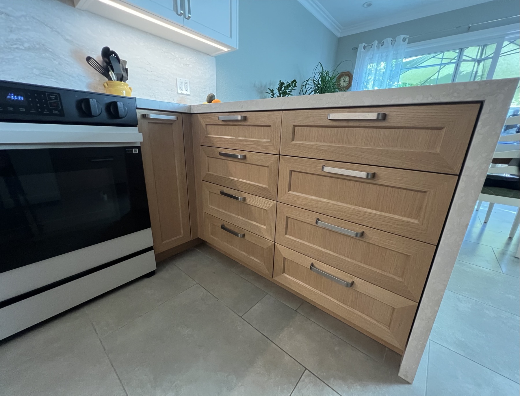 Warm-wood drawer bank beside the range under the stone counter
