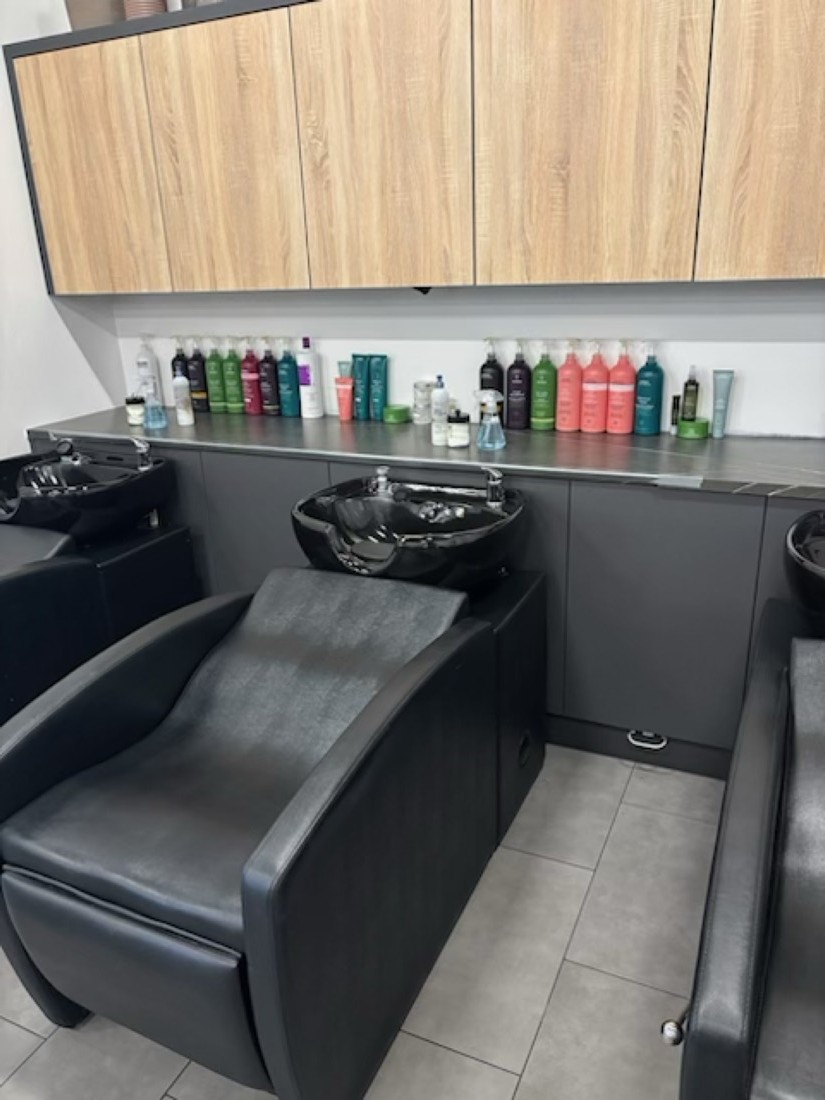 Salon wash stations with wood-grain wall cabinets and dark base cabinets